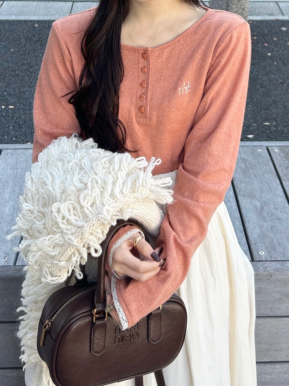 ブラウン系のバッグ、ホワイト系のスカート、ホワイト系のベストを着用したレディースの冬コーディネートの3枚目の写真