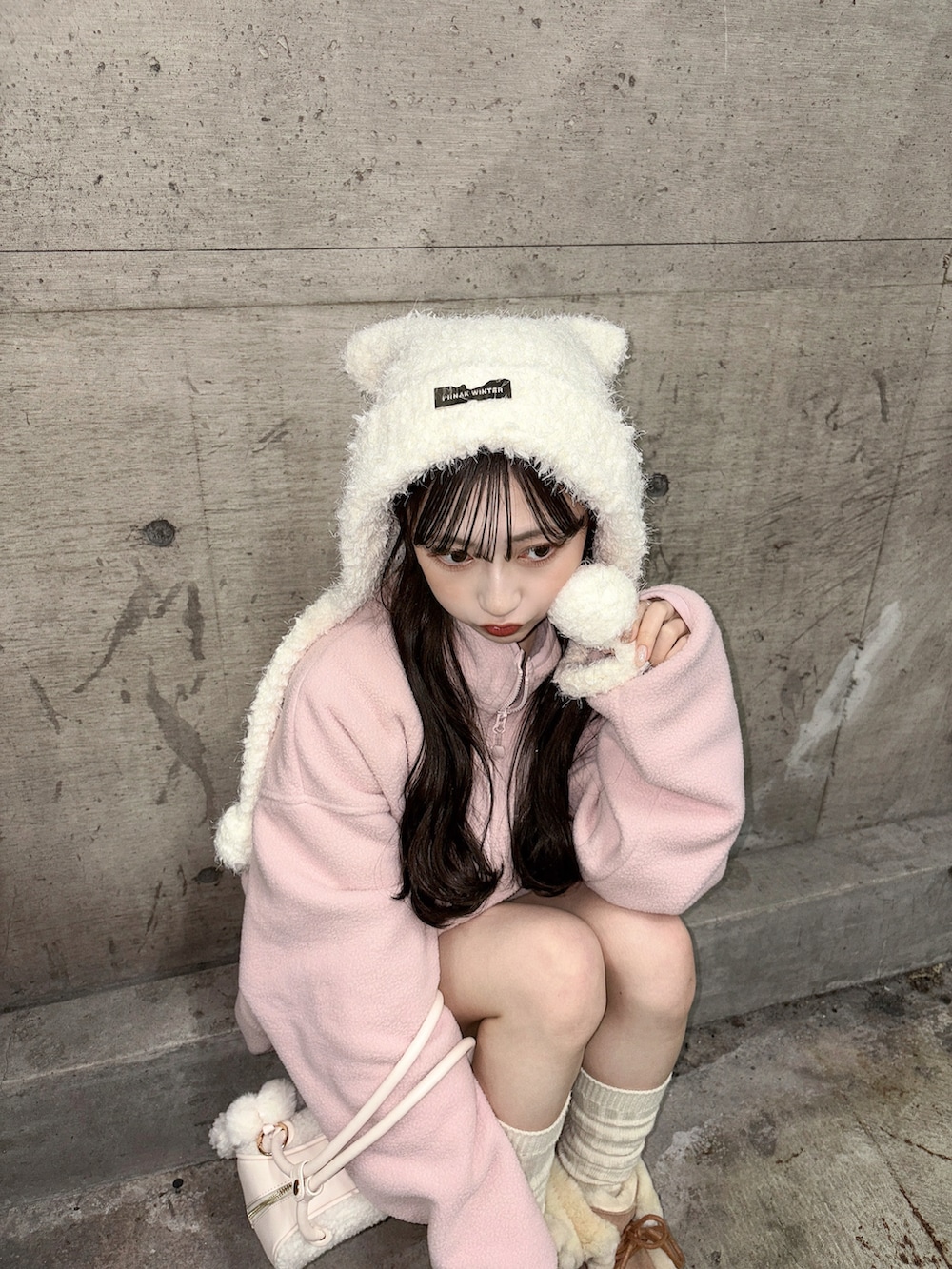 ピンク系のスウェット、ホワイト系のボストンバッグ、ベージュ系のブーツを着用したレディースの冬コーディネートの4枚目の写真