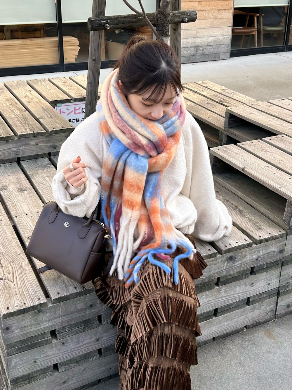 ブラウン系のバッグ、ブラウン系のスカート、ブラウン系のブーツを着用したレディースの冬コーディネートの5枚目の写真