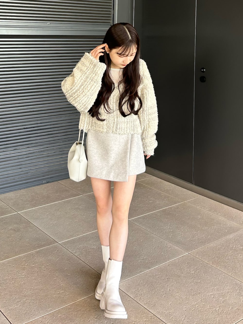 ホワイト系のブーツ、ホワイト系のショルダーバッグ、ホワイト系のカーディガン/ボレロを着用したレディースの冬コーディネートの2枚目の写真