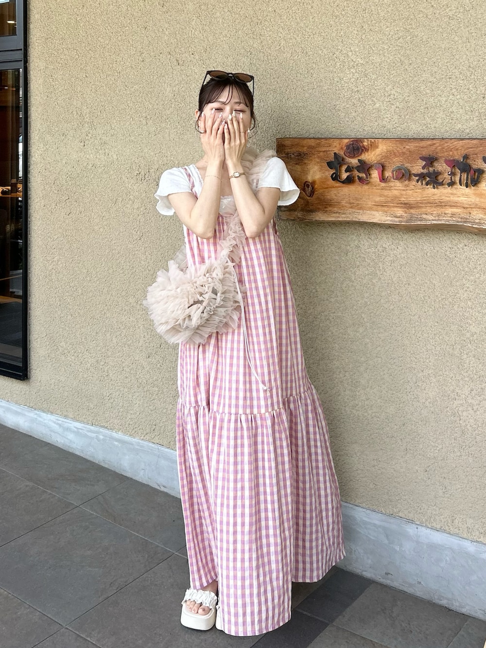 ピンク系のハンドバッグ、ホワイト系のサンダル、ホワイト系のトップスを着用したレディースの夏コーディネートの2枚目の写真