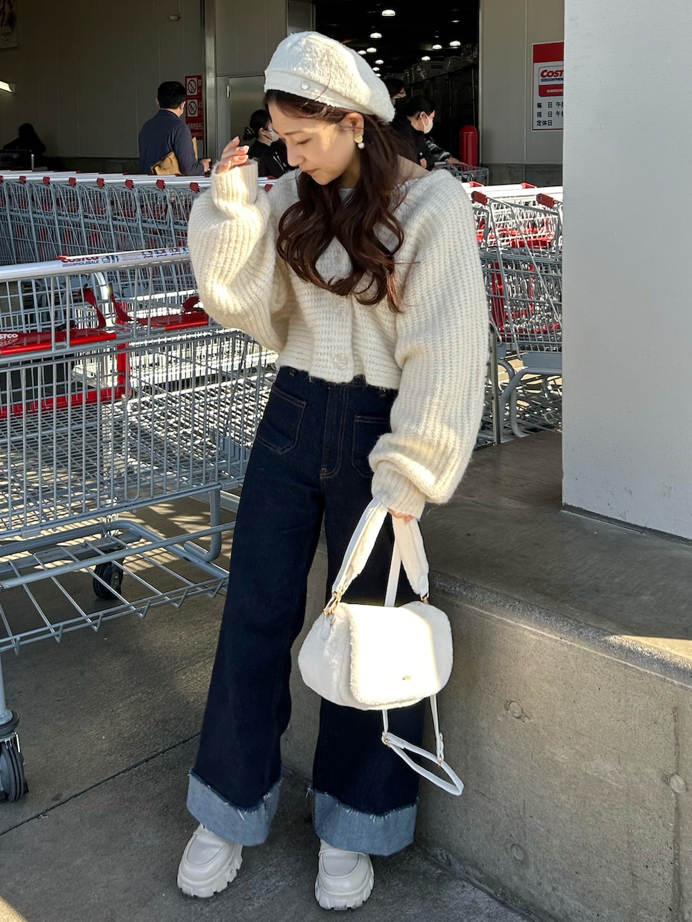 ブルー系のデニムパンツ、ホワイト系のショルダーバッグ、ホワイト系のローファーを着用したレディースの冬コーディネートの2枚目の写真