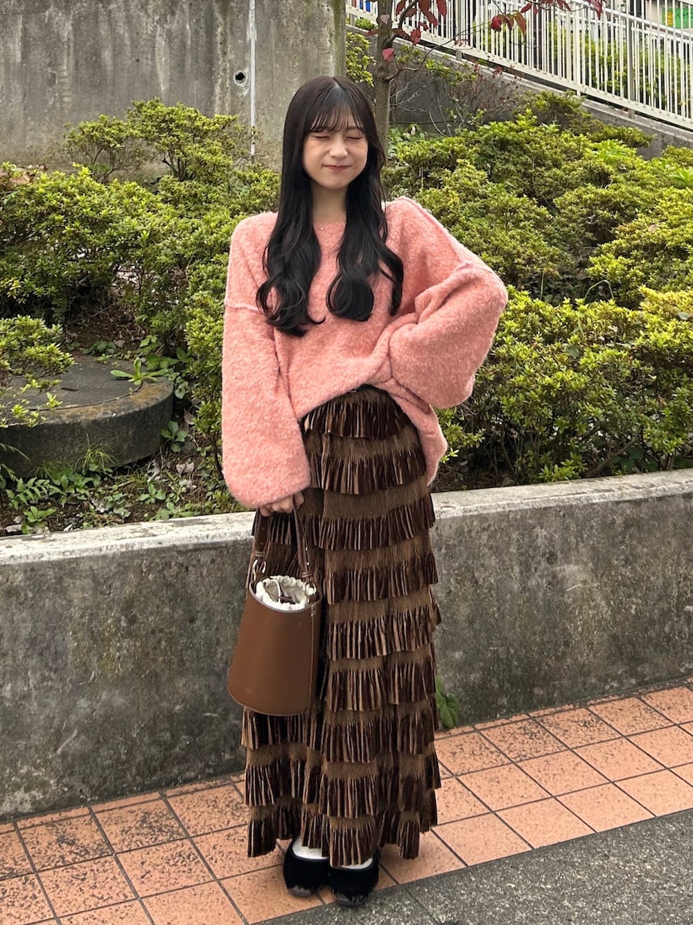 ピンク系のニット/セーター、ブラウン系のスカート、ブラウン系のハンドバッグを着用したレディースの秋コーディネートの4枚目の写真