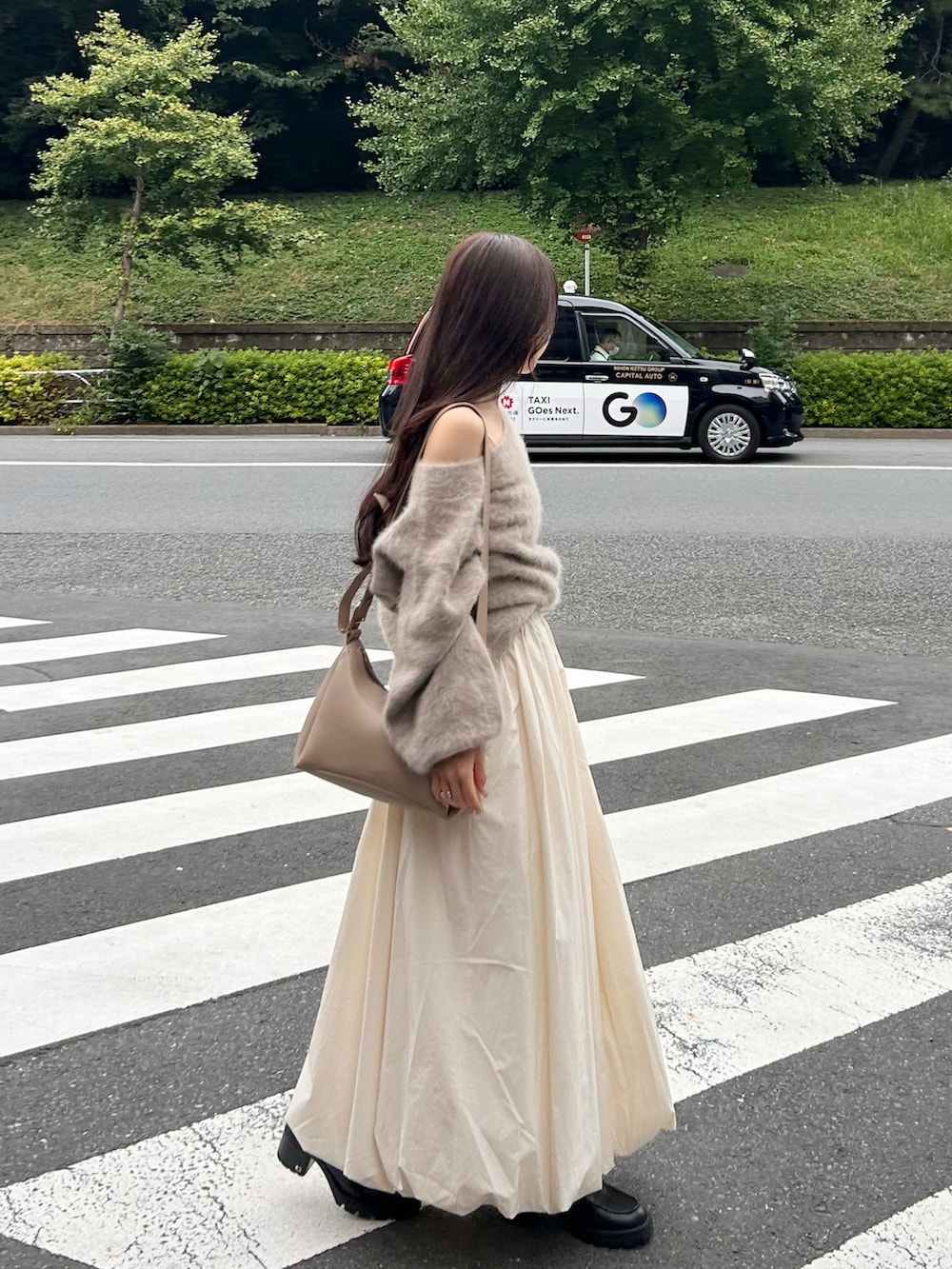 ベージュ系のバッグ、ブラウン系のニット/セーター、ホワイト系のスカートを着用したレディースの秋コーディネートの4枚目の写真