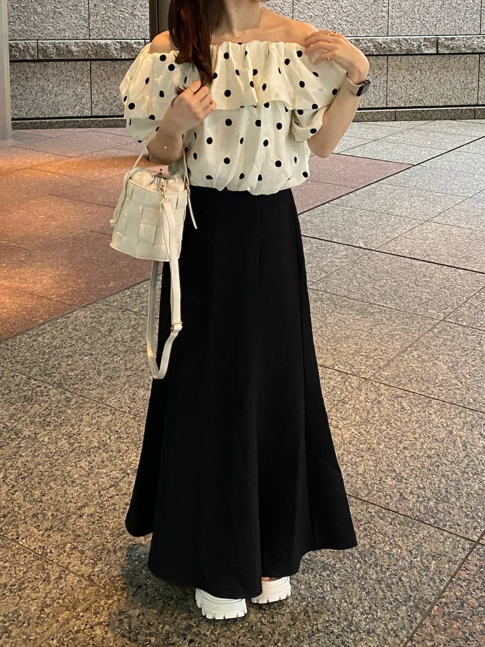 ホワイト系のトップス、ブラック系のスカート、ホワイト系のバッグを着用したレディースの夏コーディネートの3枚目の写真
