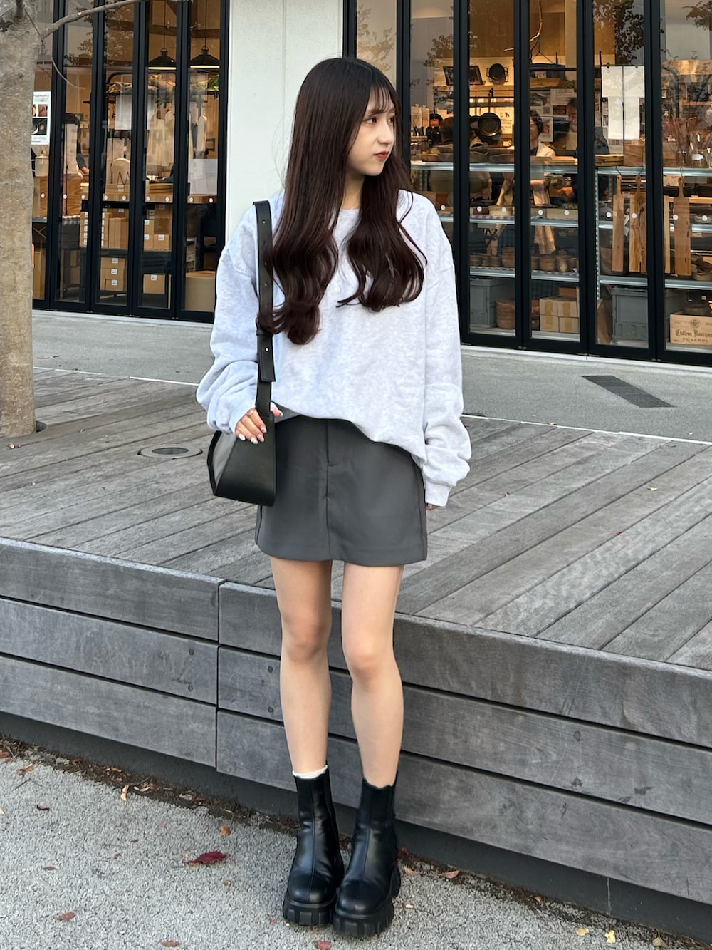 グレー系のスカート、グレー系のスウェット、ブラック系のブーツを着用したレディースの秋コーディネートの3枚目の写真