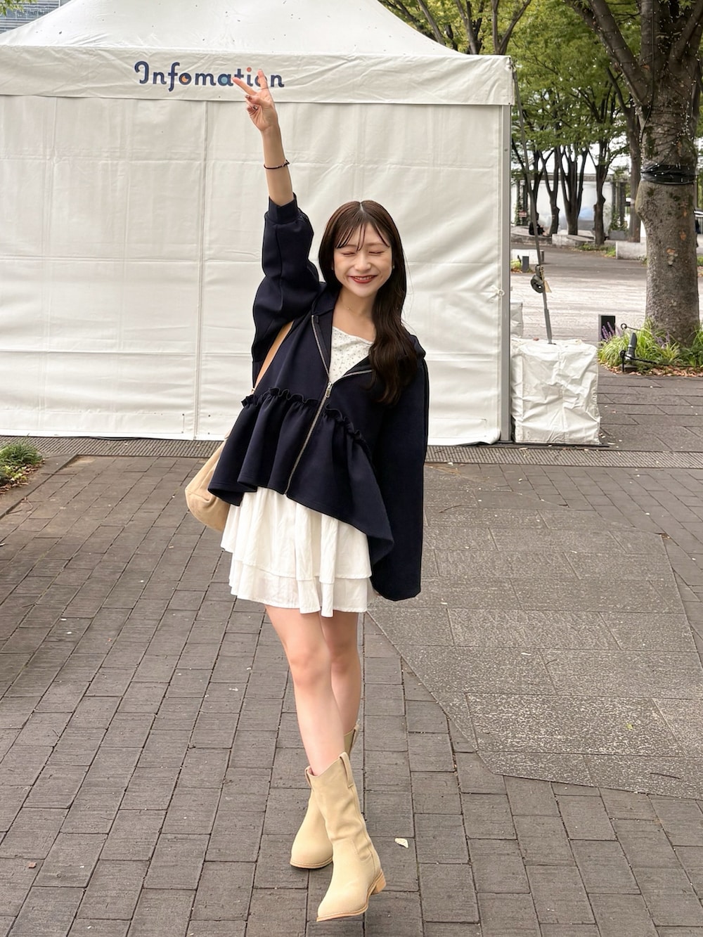 ベージュ系のブーツ、ブラウン系のパーカー、ホワイト系のスカートを着用したレディースの秋コーディネートの2枚目の写真