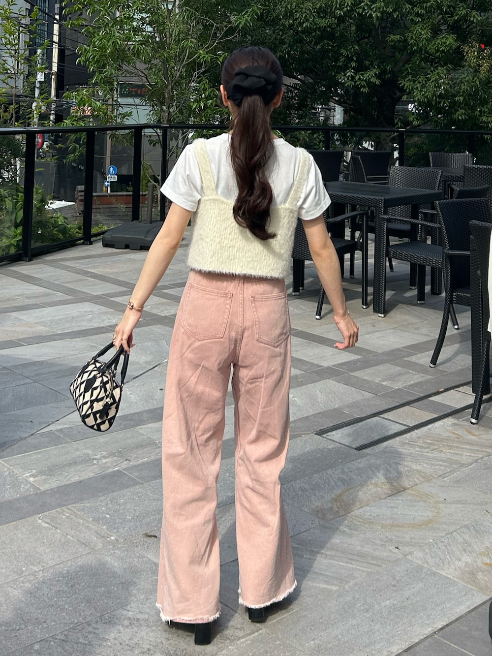 ブラック系のバッグ、ピンク系のデニムパンツ、ホワイト系のベストを着用したレディースの秋コーディネートの3枚目の写真