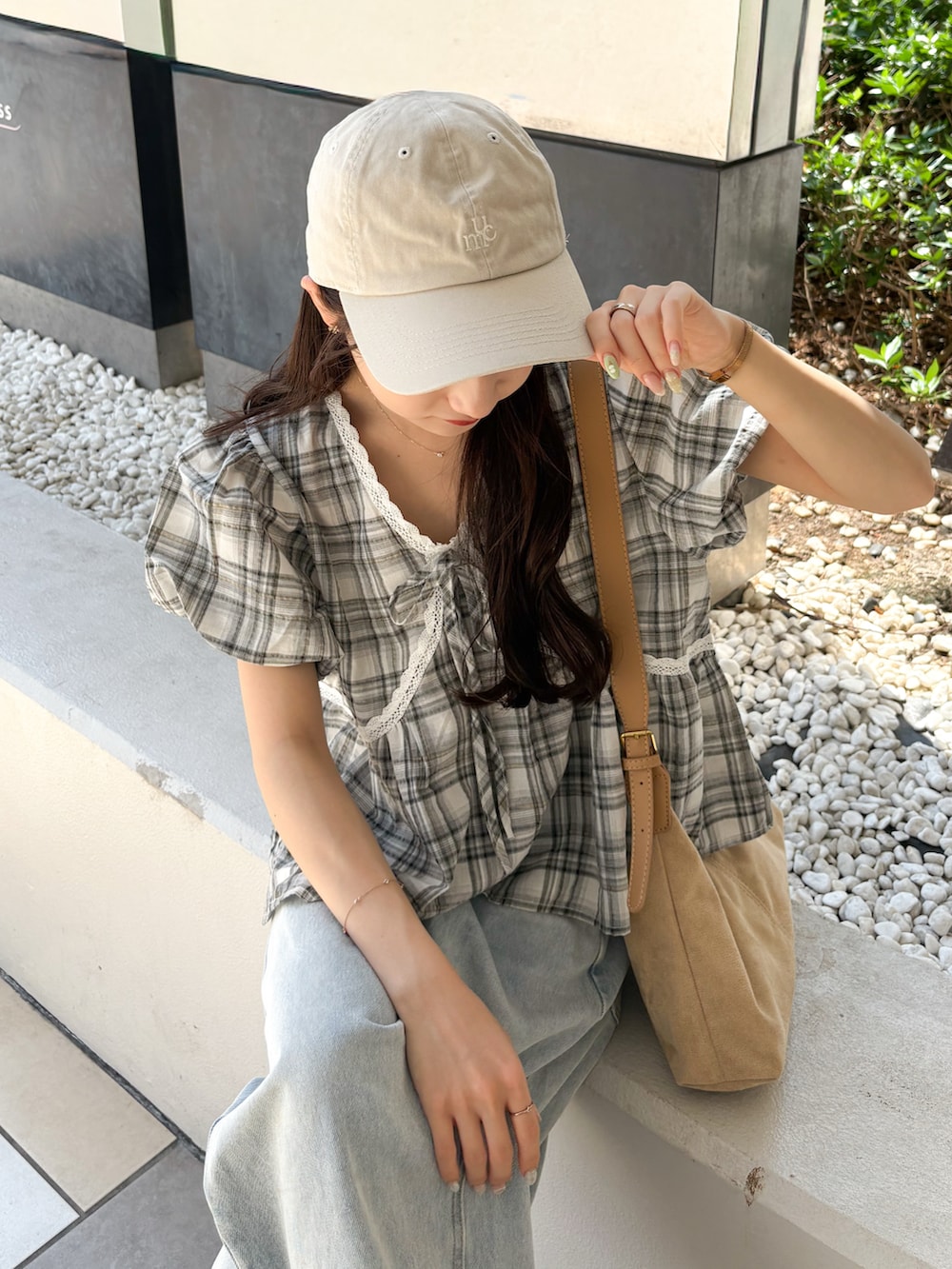 ブラック系のトップス、ベージュ系のショルダーバッグ、ブルー系のデニムパンツを着用したレディースの秋コーディネートの4枚目の写真