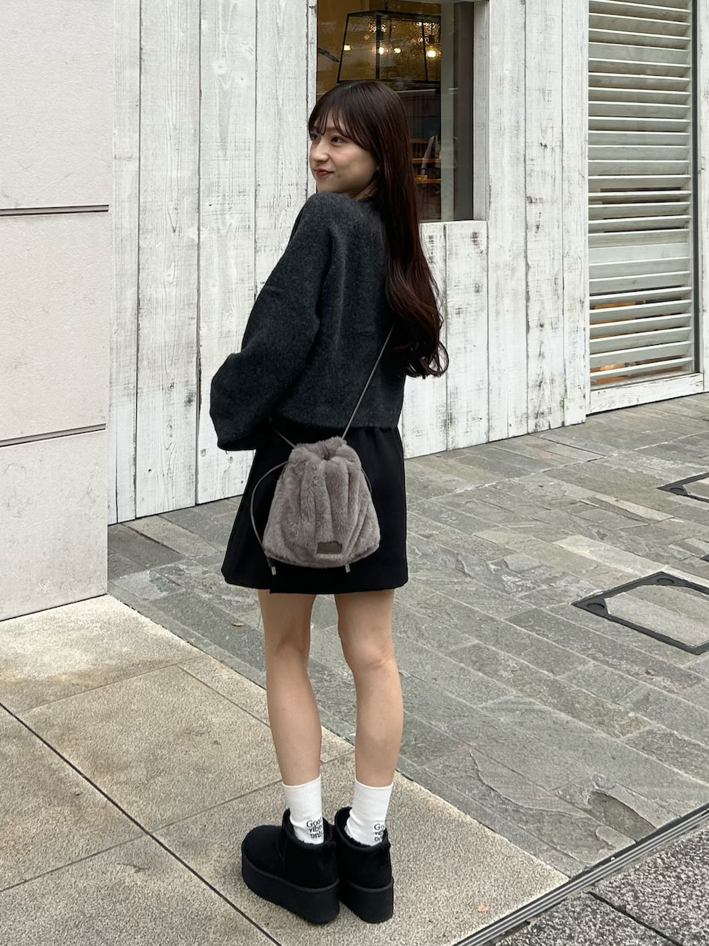 ブラック系のブーツ、グレー系のニット/セーター、ブラック系のスカートを着用したレディースの秋コーディネートの3枚目の写真