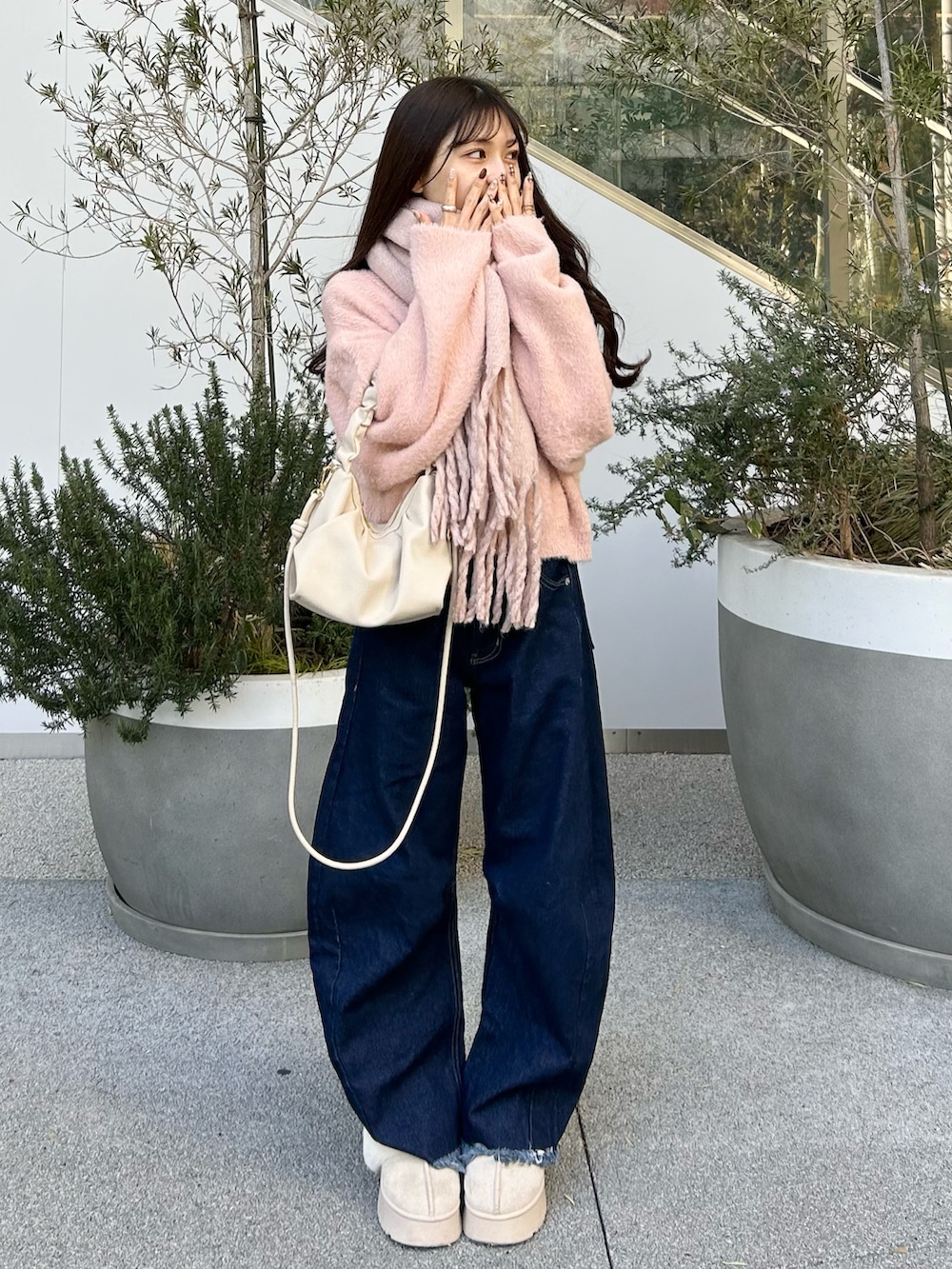 ブルー系のデニムパンツ、ピンク系のニット/セーター、ホワイト系のショルダーバッグを着用したレディースの冬コーディネートの4枚目の写真