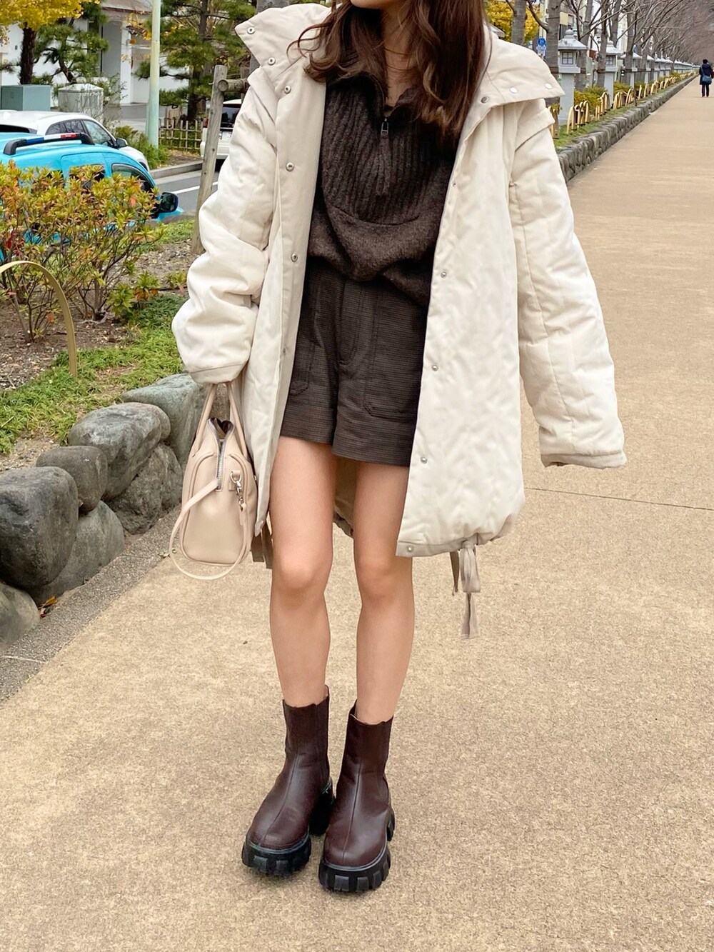 ホワイト系のダウンジャケット/コート、ブラウン系のブーツ、ベージュ系のバッグを着用したレディースの冬コーディネートの2枚目の写真