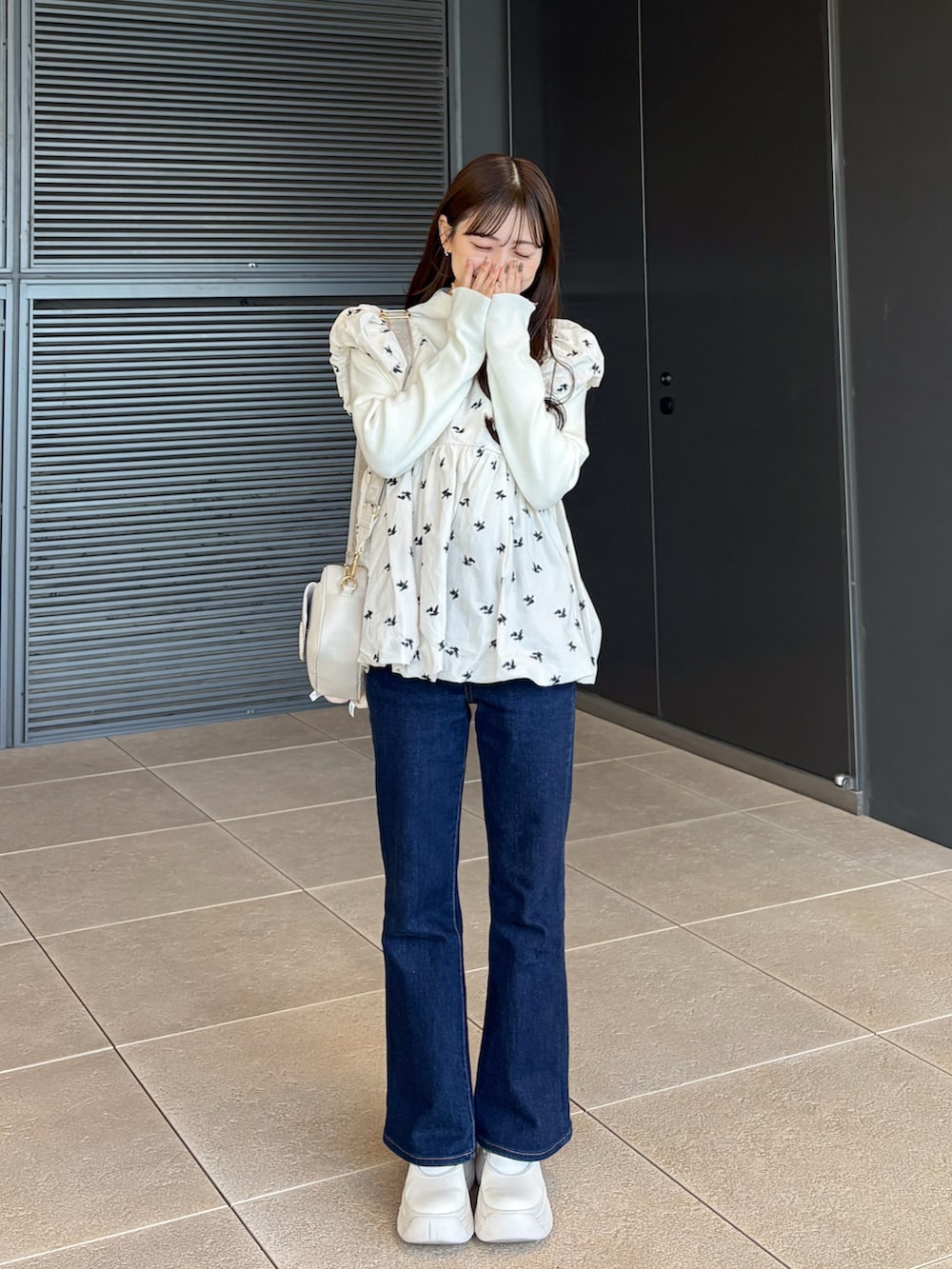 ブルー系のデニムパンツ、ホワイト系のシューズ、ホワイト系のショルダーバッグを着用したレディースの冬コーディネートの3枚目の写真