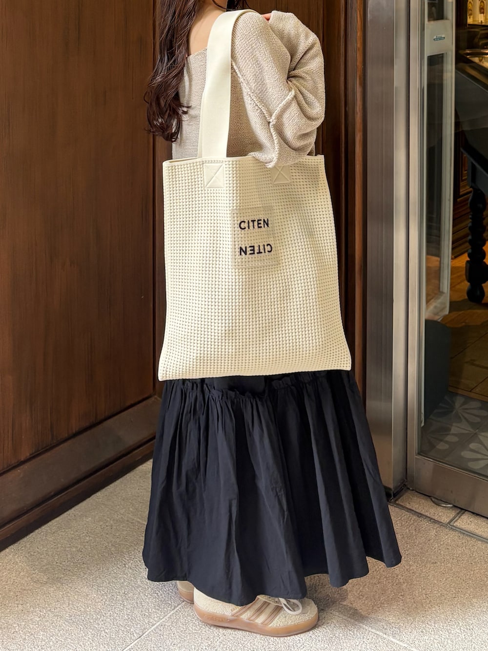 ブラック系のスカート、ベージュ系のニット/セーター、ホワイト系のトートバッグを着用したレディースの秋コーディネートの4枚目の写真