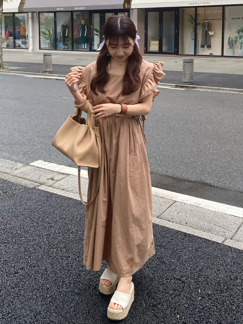 ベージュ系のバッグ、ベージュ系のワンピース、ホワイト系のサンダルを着用したレディースの夏コーディネートの2枚目の写真