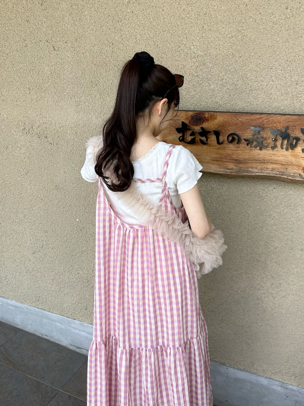 ピンク系のハンドバッグ、ホワイト系のサンダル、ホワイト系のトップスを着用したレディースの夏コーディネートの3枚目の写真