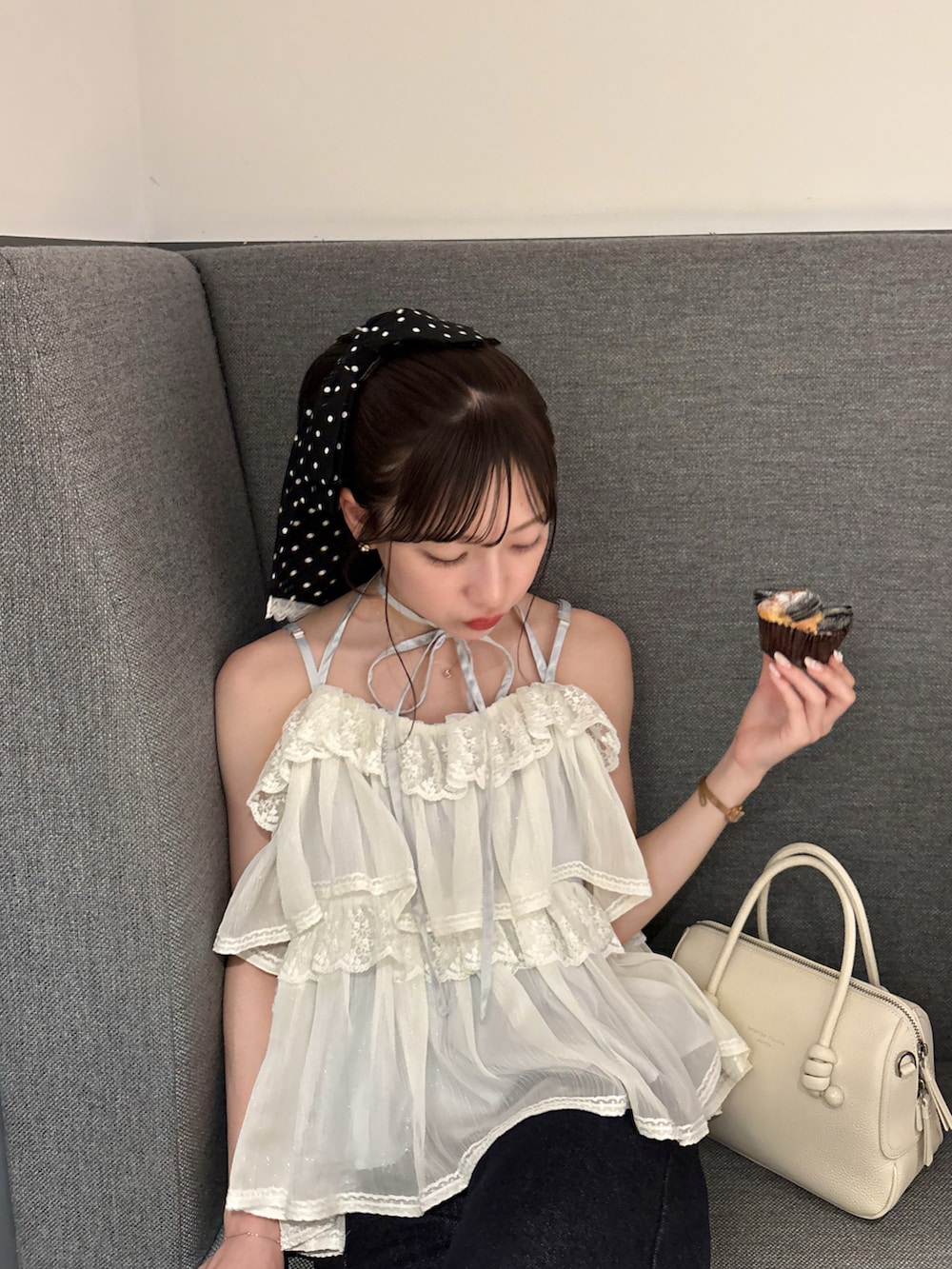 ホワイト系のハンドバッグ、ブルー系のデニムパンツ、ホワイト系のトップスを着用したレディースの夏コーディネートの4枚目の写真