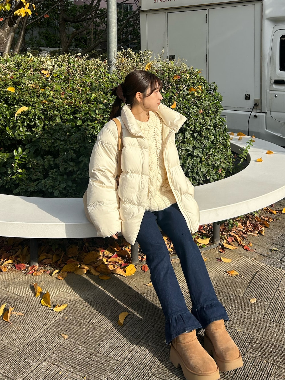 ブルー系のデニムパンツ、ホワイト系のダウンジャケット/コート、ベージュ系のショルダーバッグを着用したレディースの冬コーディネートの5枚目の写真