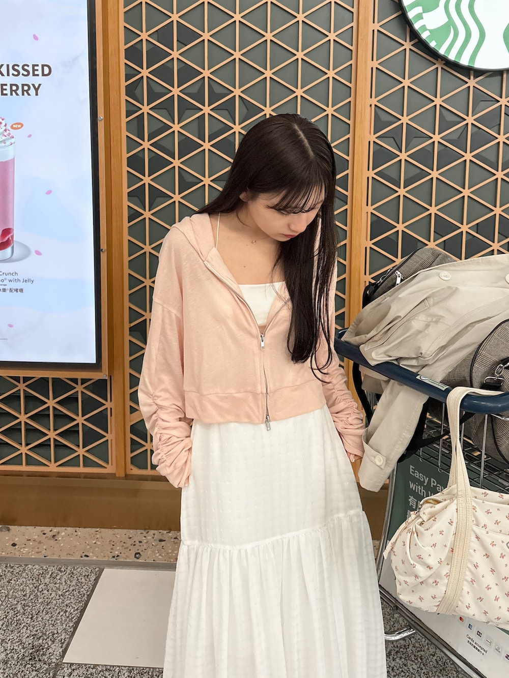 ホワイト系のスカート、ベージュ系のボストンバッグ、ホワイト系のトレンチコートを着用したレディースの春コーディネートの5枚目の写真
