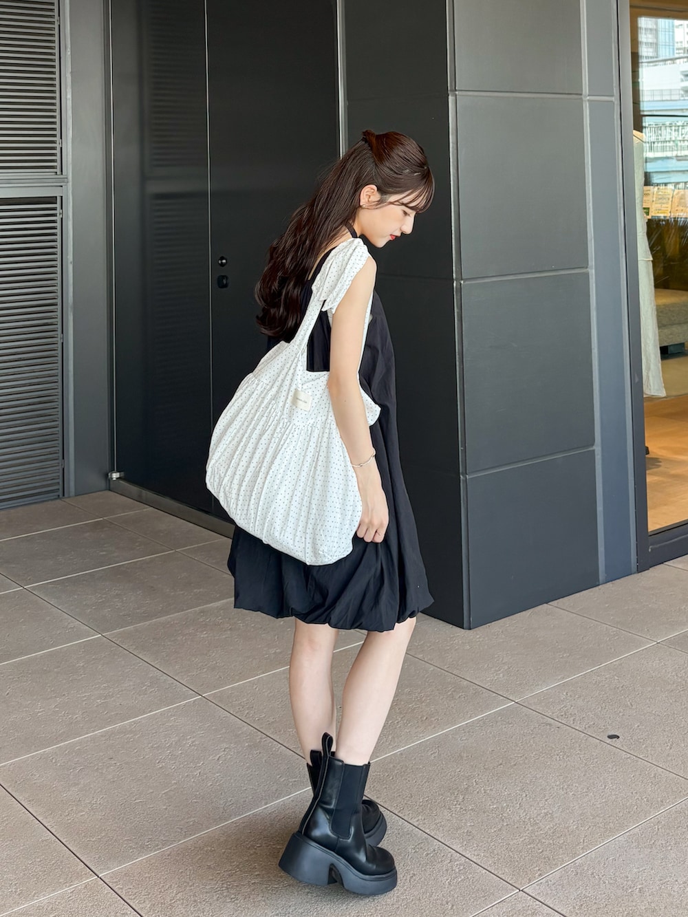 ブラック系のワンピース、ブラック系のブーツ、ホワイト系のカーディガン/ボレロを着用したレディースの夏コーディネートの3枚目の写真