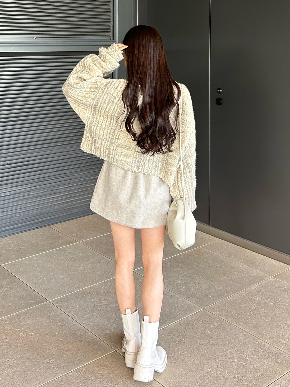 ホワイト系のブーツ、ホワイト系のショルダーバッグ、ホワイト系のカーディガン/ボレロを着用したレディースの冬コーディネートの3枚目の写真