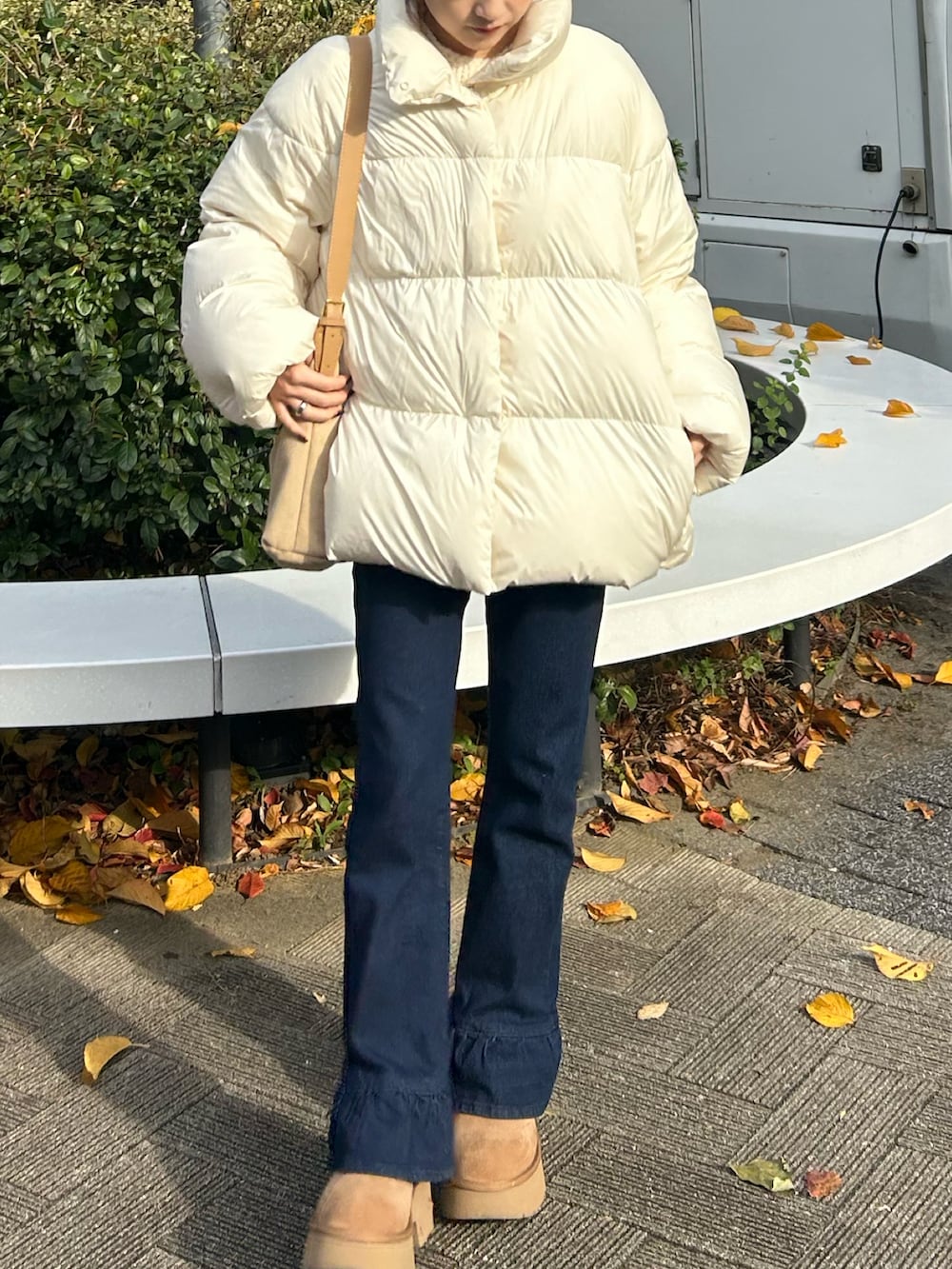 ブルー系のデニムパンツ、ホワイト系のダウンジャケット/コート、ベージュ系のショルダーバッグを着用したレディースの冬コーディネートの2枚目の写真