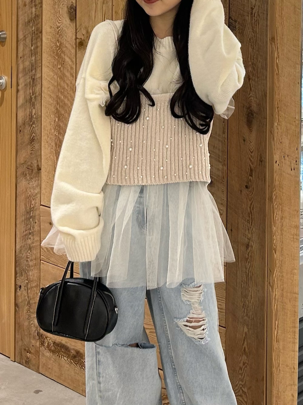 ブルー系のデニムパンツ、ホワイト系のベスト、ホワイト系のニット/セーターを着用したレディースの春コーディネートの3枚目の写真