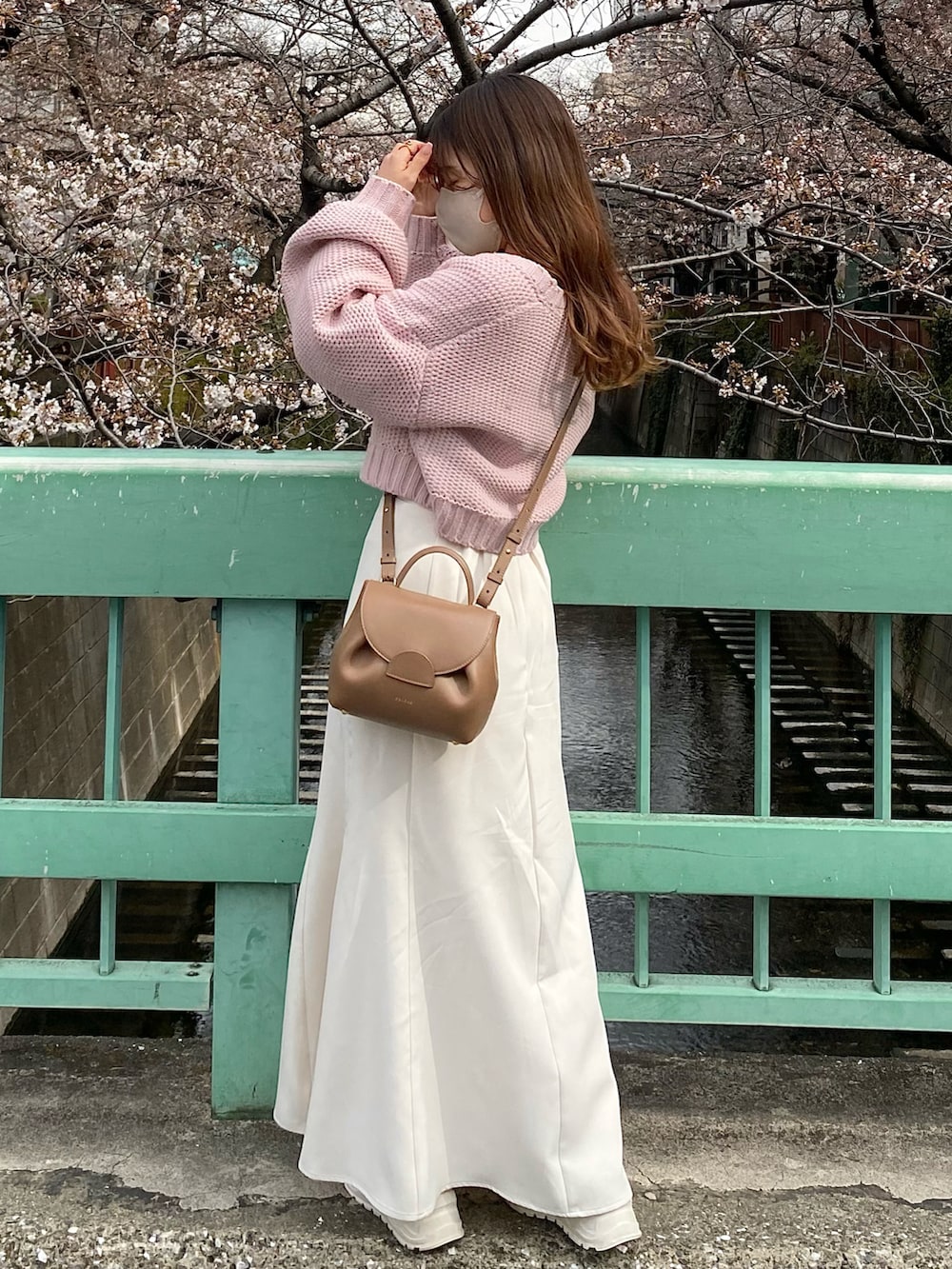 ブラウン系のバッグ、ピンク系のカーディガン/ボレロ、ホワイト系のスカートを着用したレディースの春コーディネートの3枚目の写真