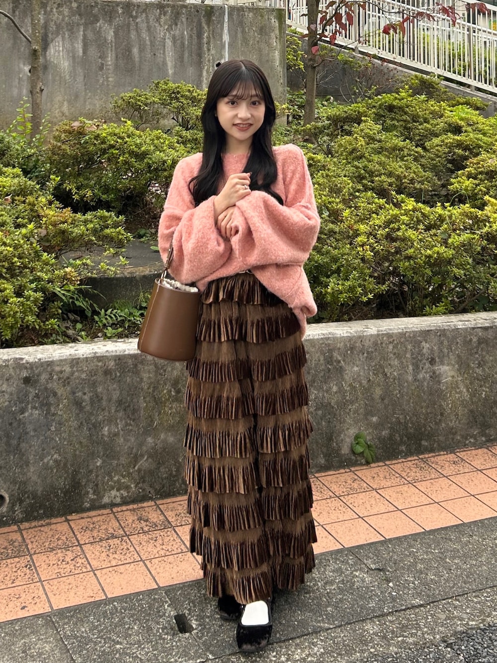 ピンク系のニット/セーター、ブラウン系のスカート、ブラウン系のハンドバッグを着用したレディースの秋コーディネートの2枚目の写真