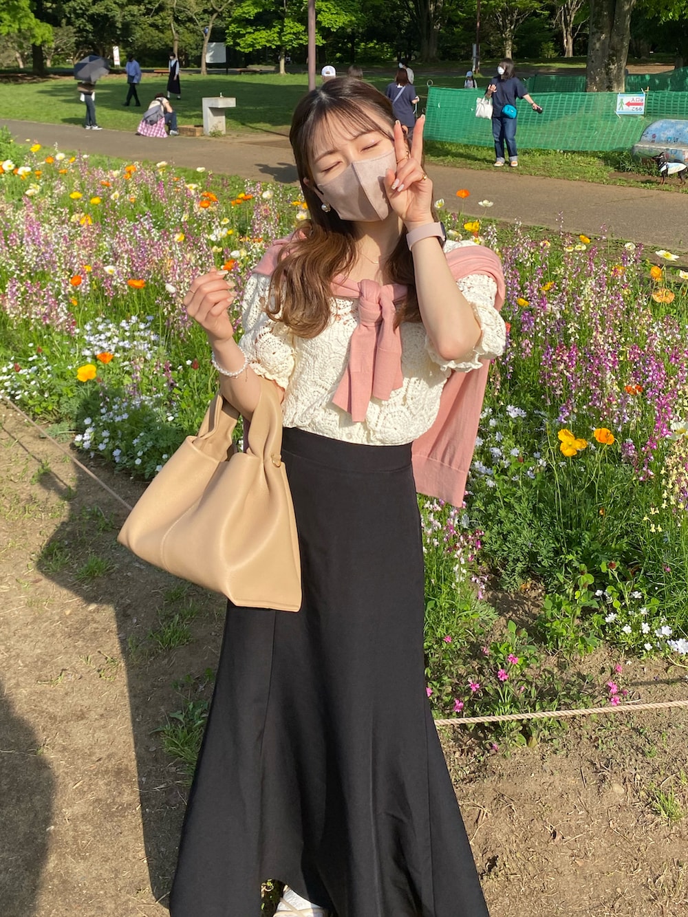 ブラック系のスカート、ピンク系のカーディガン/ボレロ、ベージュ系のバッグを着用したレディースの春コーディネートの2枚目の写真