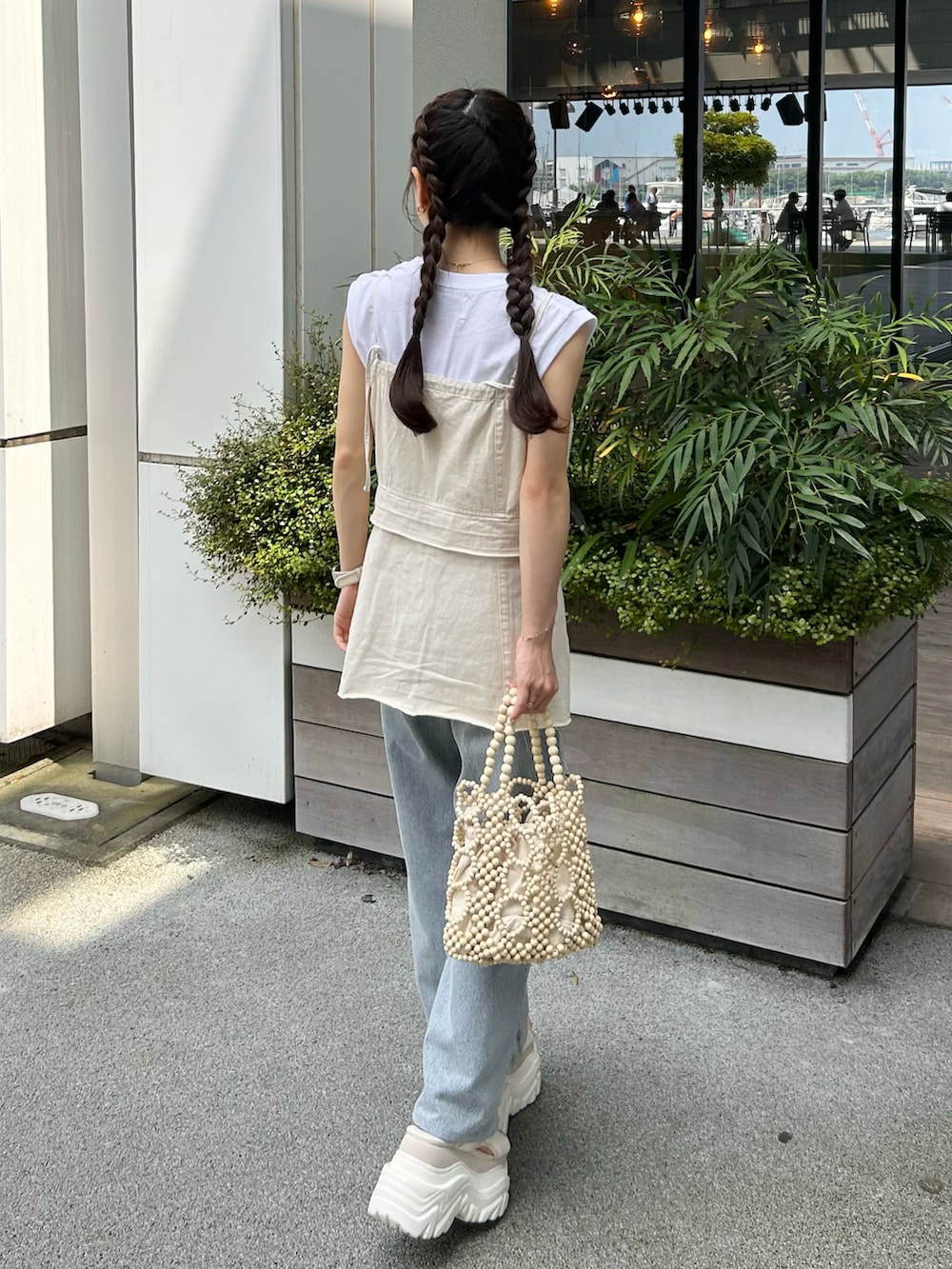 ホワイト系のハンドバッグ、ホワイト系のキャミソール、ホワイト系のTシャツ/カットソーを着用したレディースの夏コーディネートの3枚目の写真