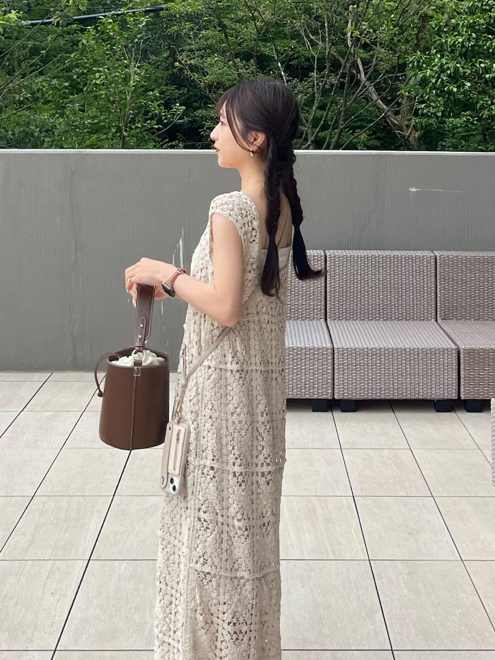 ブラウン系のハンドバッグ、ホワイト系のワンピース、ホワイト系のサンダルを着用したレディースの夏コーディネートの3枚目の写真