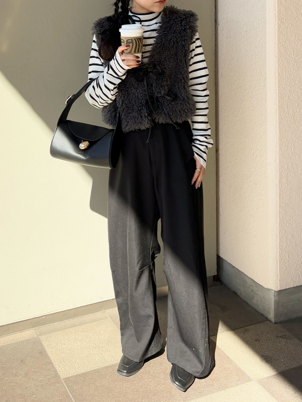 ブラック系のその他パンツ、ブラック系のバッグ、ホワイト系のニット/セーターを着用したレディースの冬コーディネートの2枚目の写真