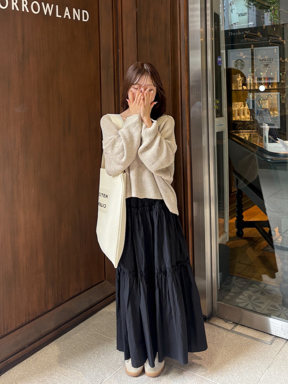 ブラック系のスカート、ベージュ系のニット/セーター、ホワイト系のトートバッグを着用したレディースの秋コーディネートの3枚目の写真