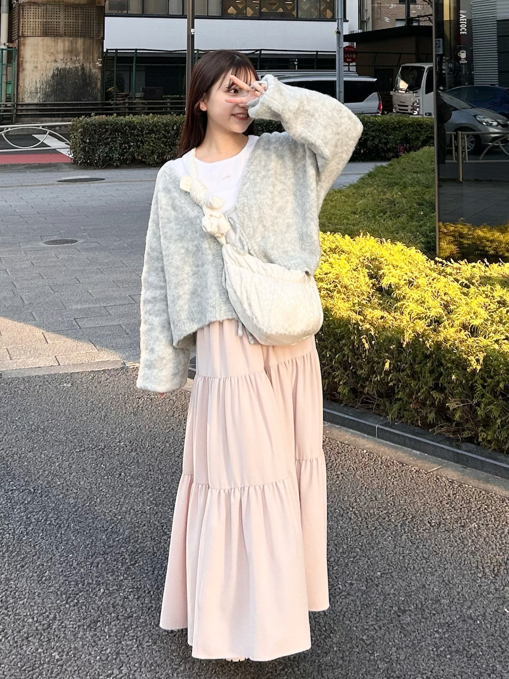 グレー系のカーディガン/ボレロ、ホワイト系のスカート、ホワイト系のトップスを着用したレディースの春コーディネートの2枚目の写真