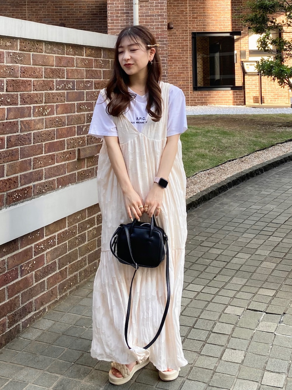 ホワイト系のサンダル、ブラック系のバッグ、ホワイト系のワンピースを着用したレディースの夏コーディネートの2枚目の写真