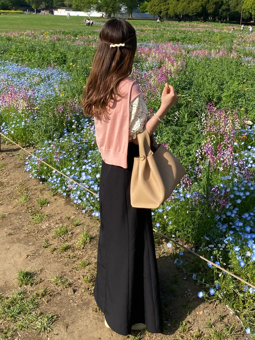 ブラック系のスカート、ピンク系のカーディガン/ボレロ、ベージュ系のバッグを着用したレディースの春コーディネートの3枚目の写真