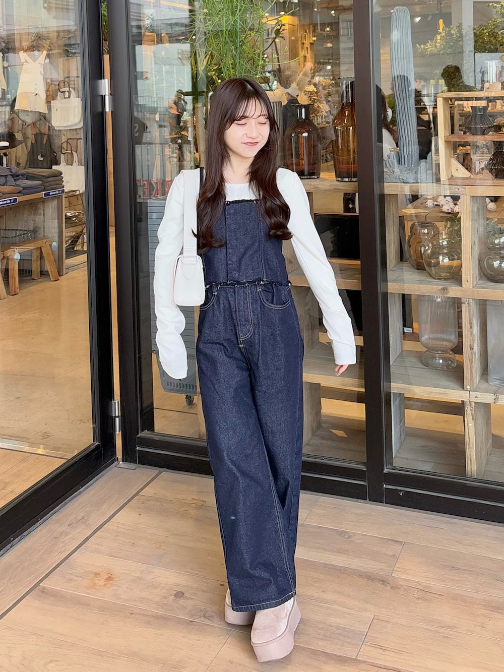 ブルー系のデニムパンツ、ブラウン系のブルゾン、ホワイト系のショルダーバッグを着用したレディースの冬コーディネートの5枚目の写真