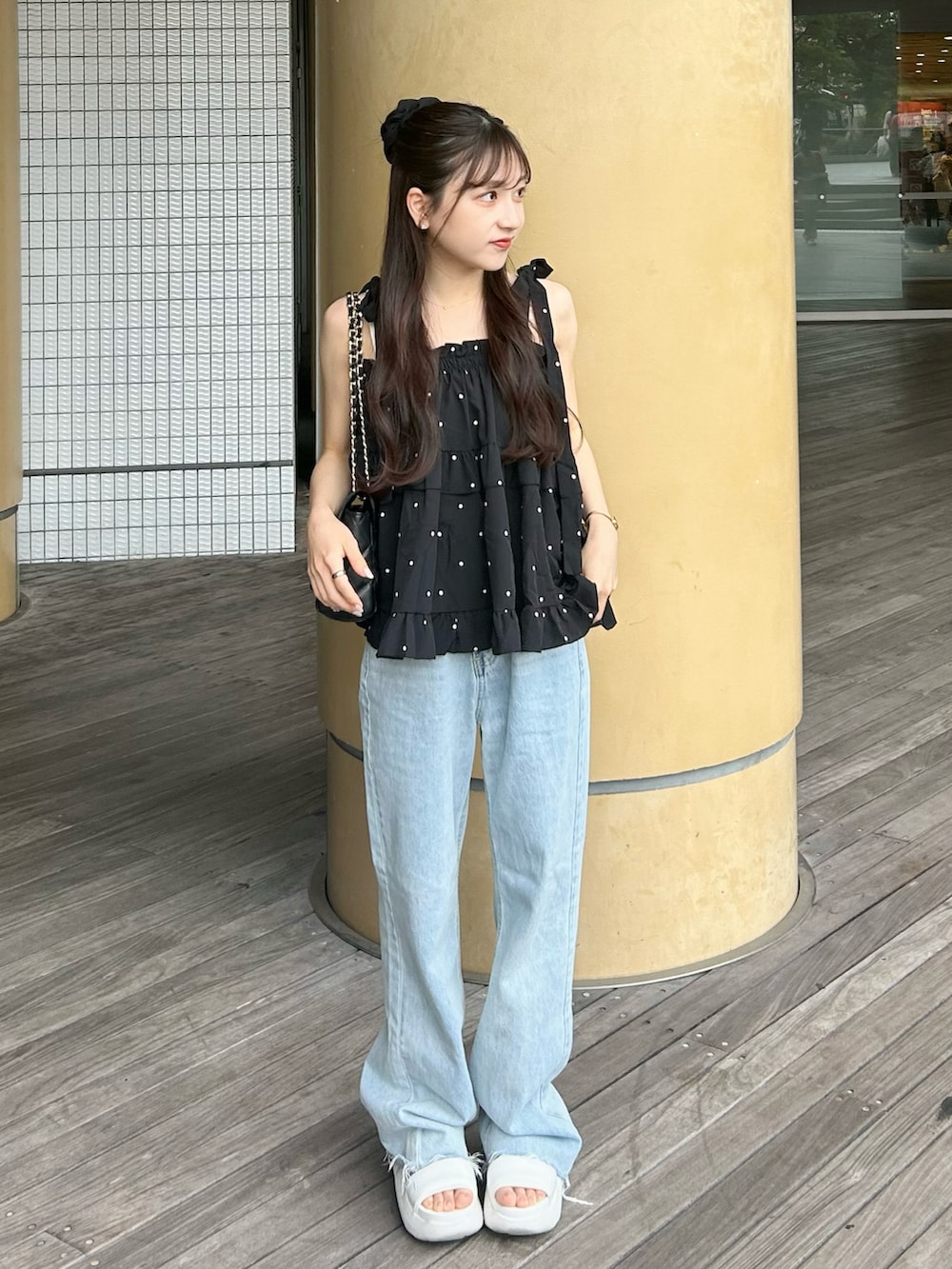 ブルー系のデニムパンツ、ブラック系のトップス、ホワイト系のサンダルを着用したレディースの夏コーディネートの4枚目の写真