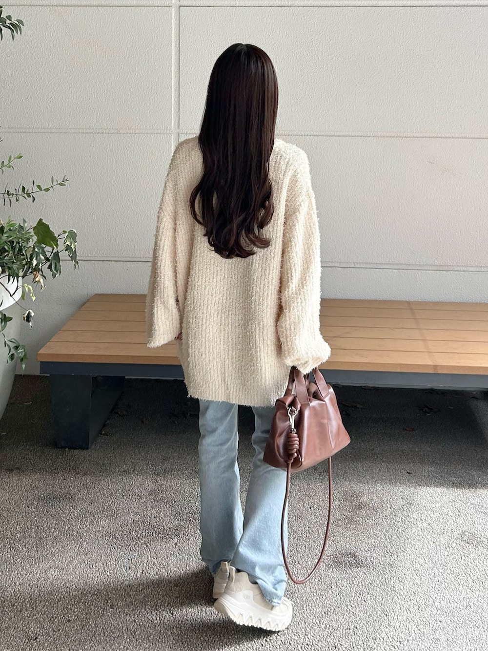 ブルー系のデニムパンツ、ブラウン系のボストンバッグ、ホワイト系のニット/セーターを着用したレディースの秋コーディネートの2枚目の写真