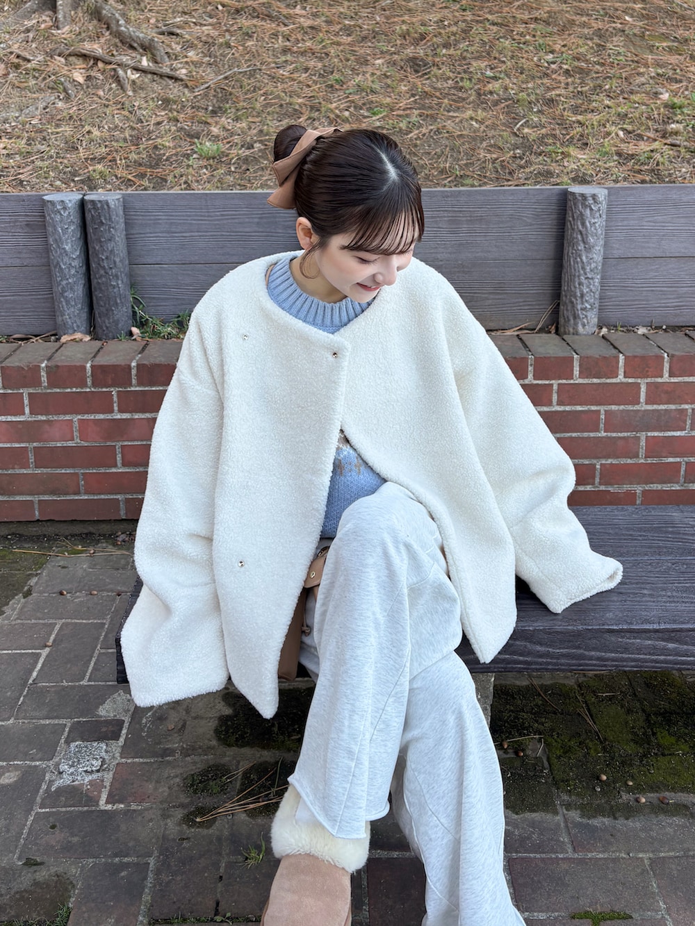 グレー系のスウェットパンツ、ホワイト系のブルゾン、ブルー系のニット/セーターを着用したレディースの冬コーディネートの3枚目の写真