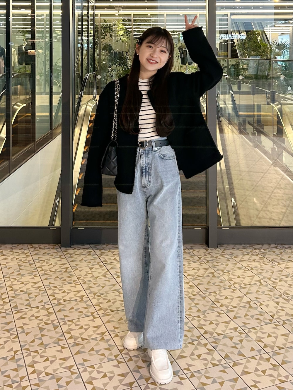 ブルー系のデニムパンツ、ブラック系のジャケット/アウター、ホワイト系のニット/セーターを着用したレディースの春コーディネートの5枚目の写真