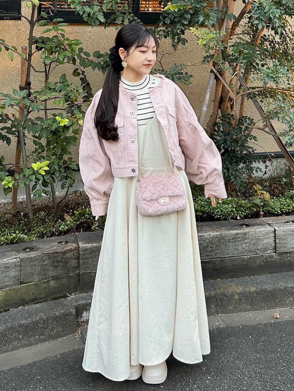 ピンク系のデニムジャケット、ホワイト系のワンピース、ホワイト系のブーツを着用したレディースの冬コーディネートの2枚目の写真