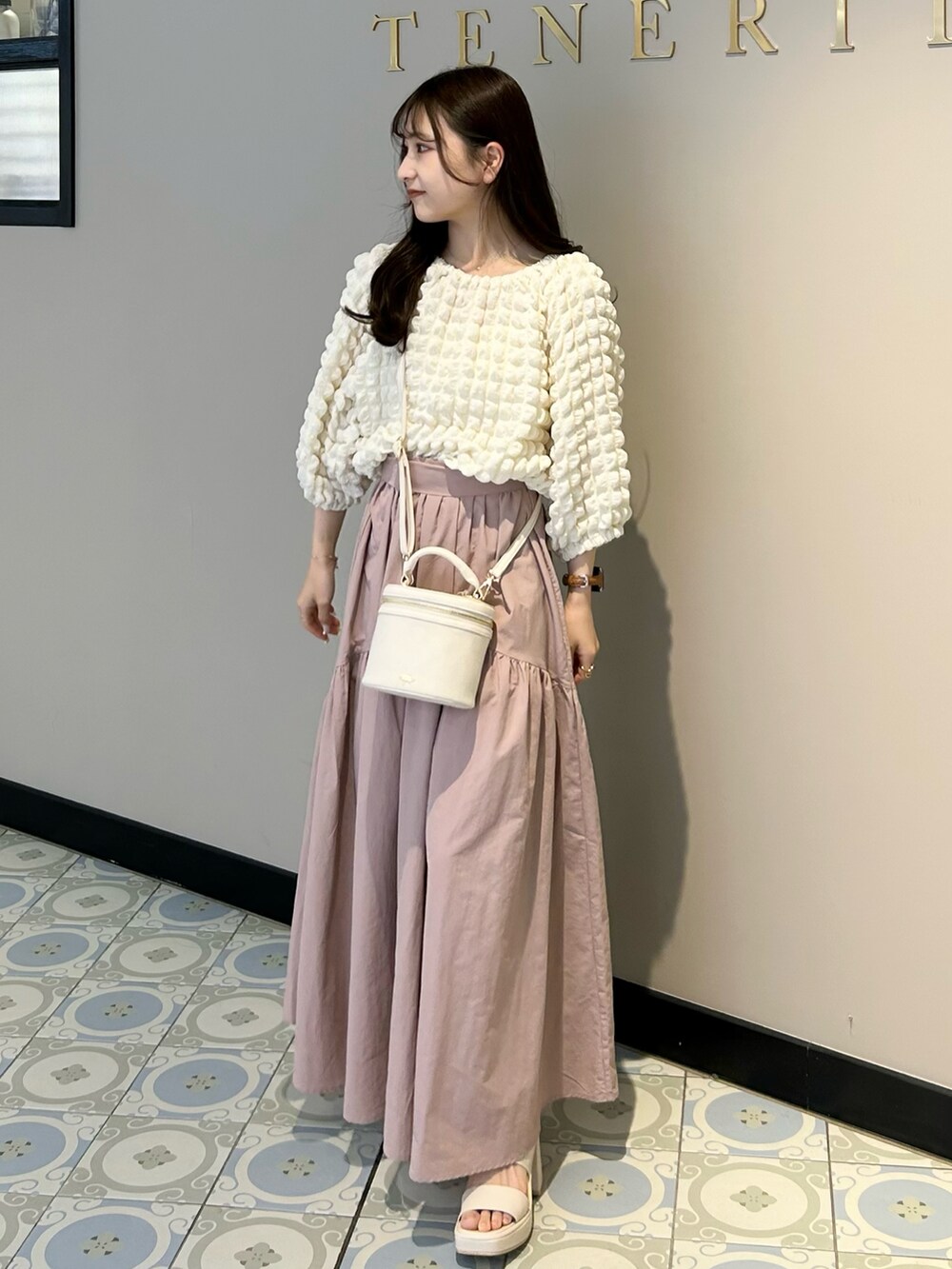 ホワイト系のショルダーバッグ、ピンク系のスカート、ホワイト系のTシャツ/カットソーを着用したレディースの春コーディネートの2枚目の写真