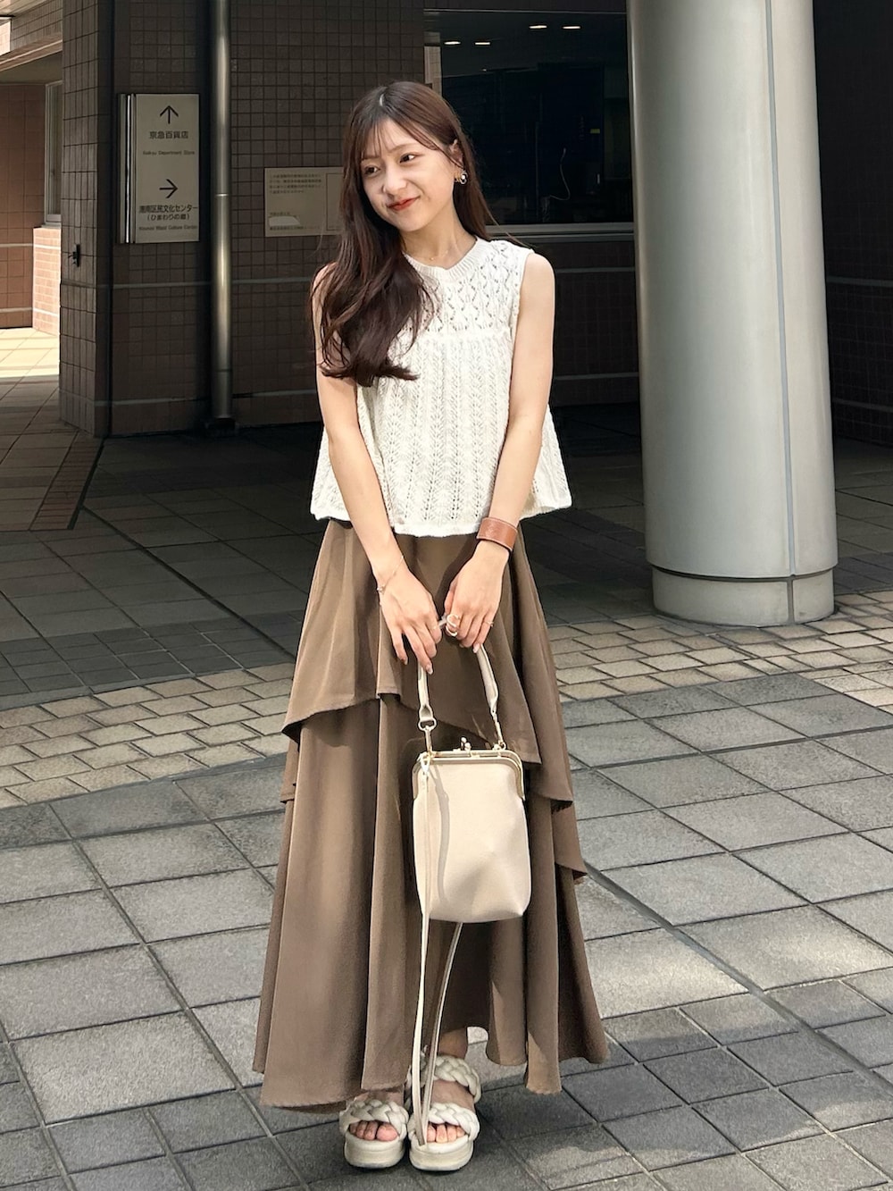 ホワイト系のベスト、ベージュ系のキャミソール、ブラウン系のスカートを着用したレディースの夏コーディネートの3枚目の写真