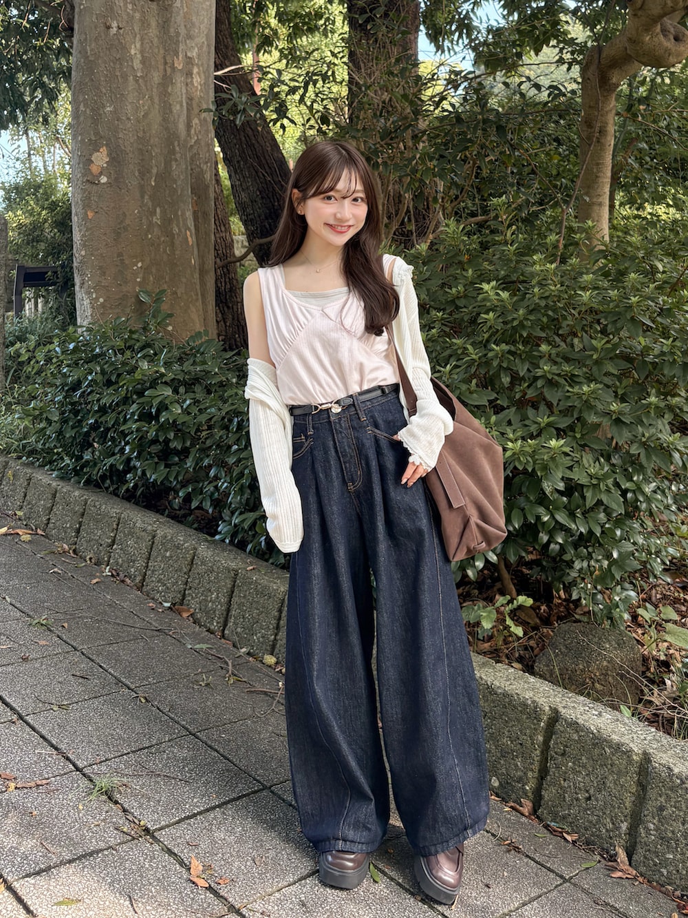 ピンク系のタンクトップ、ブルー系のデニムパンツ、ブラウン系のトートバッグを着用したレディースの秋コーディネートの2枚目の写真