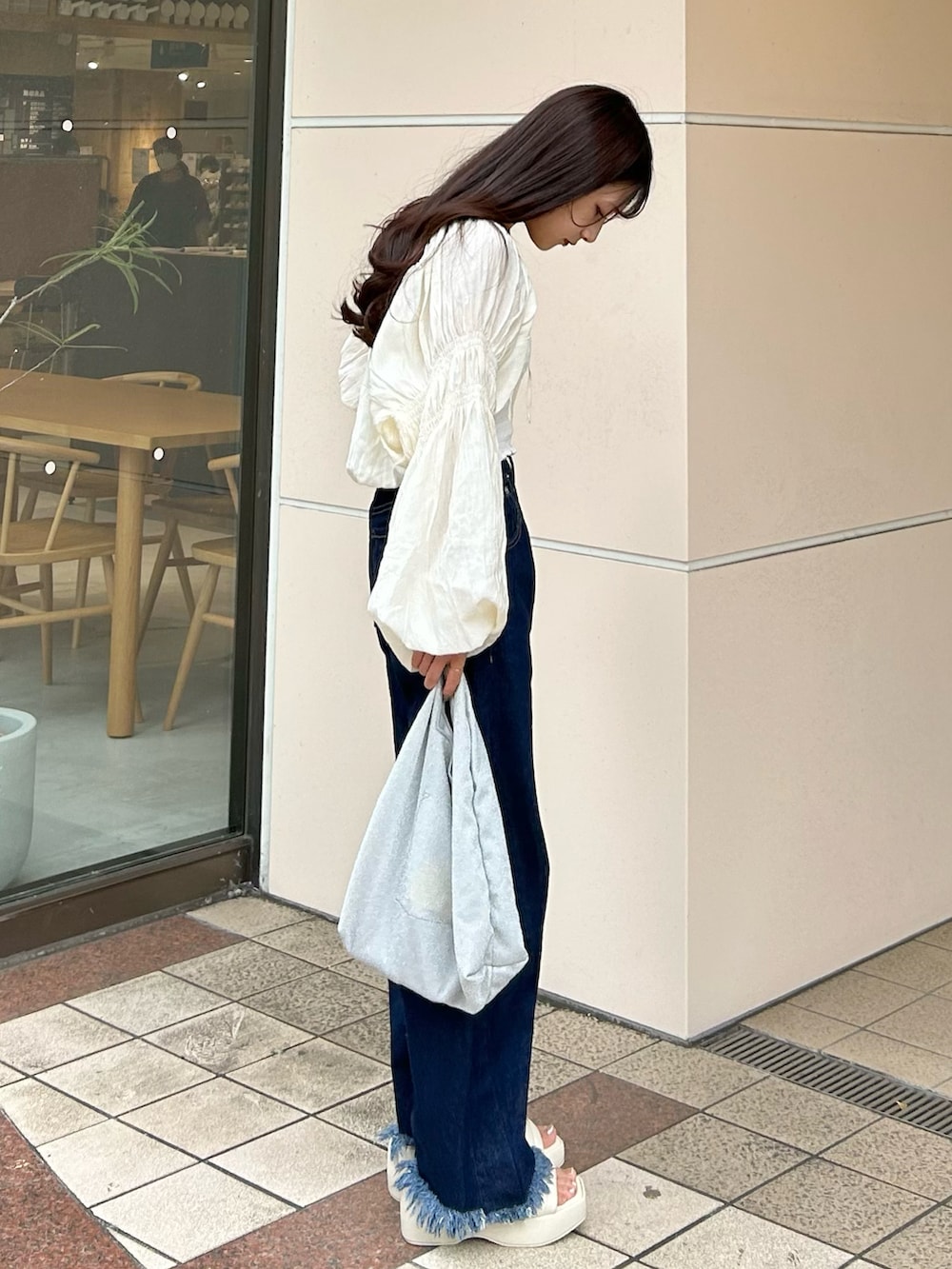 ブルー系のデニムパンツ、ホワイト系のカーディガン/ボレロ、ホワイト系のチューブトップを着用したレディースの秋コーディネートの2枚目の写真