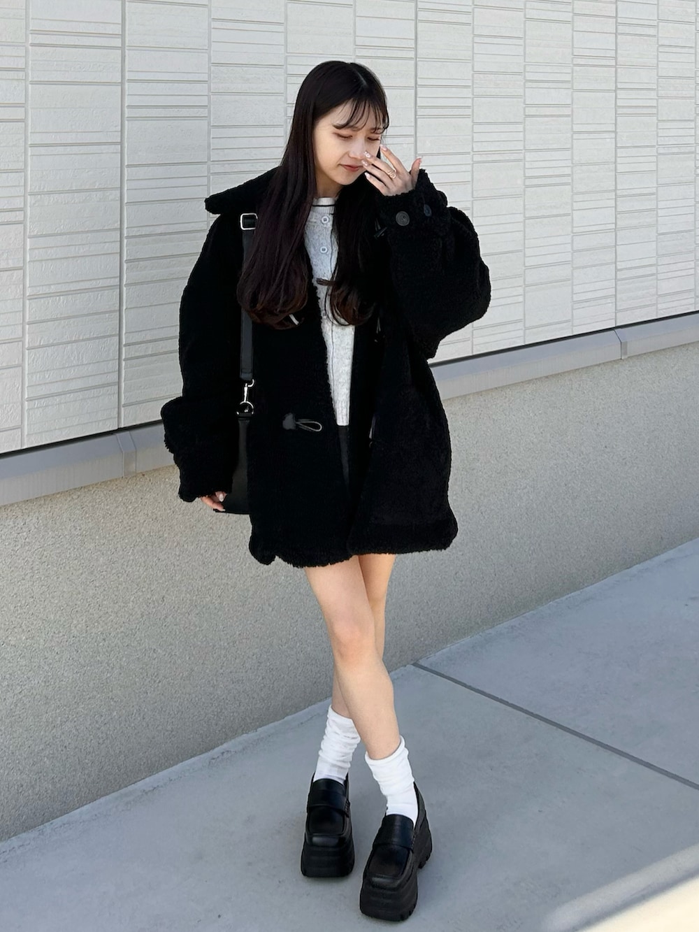 グレー系のカーディガン/ボレロ、グレー系のスカート、ブラック系のショルダーバッグを着用したレディースの冬コーディネートの3枚目の写真