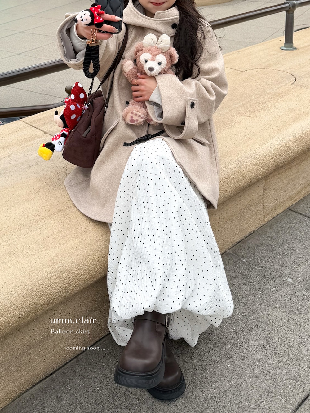 ホワイト系のスカート、ベージュ系のその他アウター、ブラウン系のボストンバッグを着用したレディースの冬コーディネートの2枚目の写真