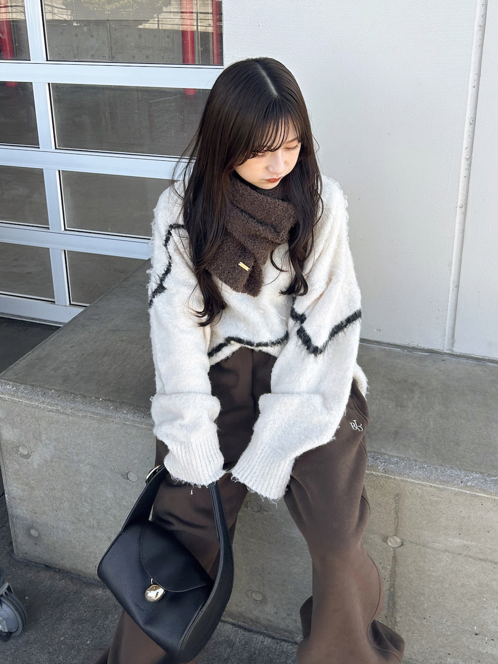 ブラウン系のスウェットパンツ、ホワイト系のニット/セーター、ブラック系のバッグを着用したレディースの冬コーディネートの3枚目の写真